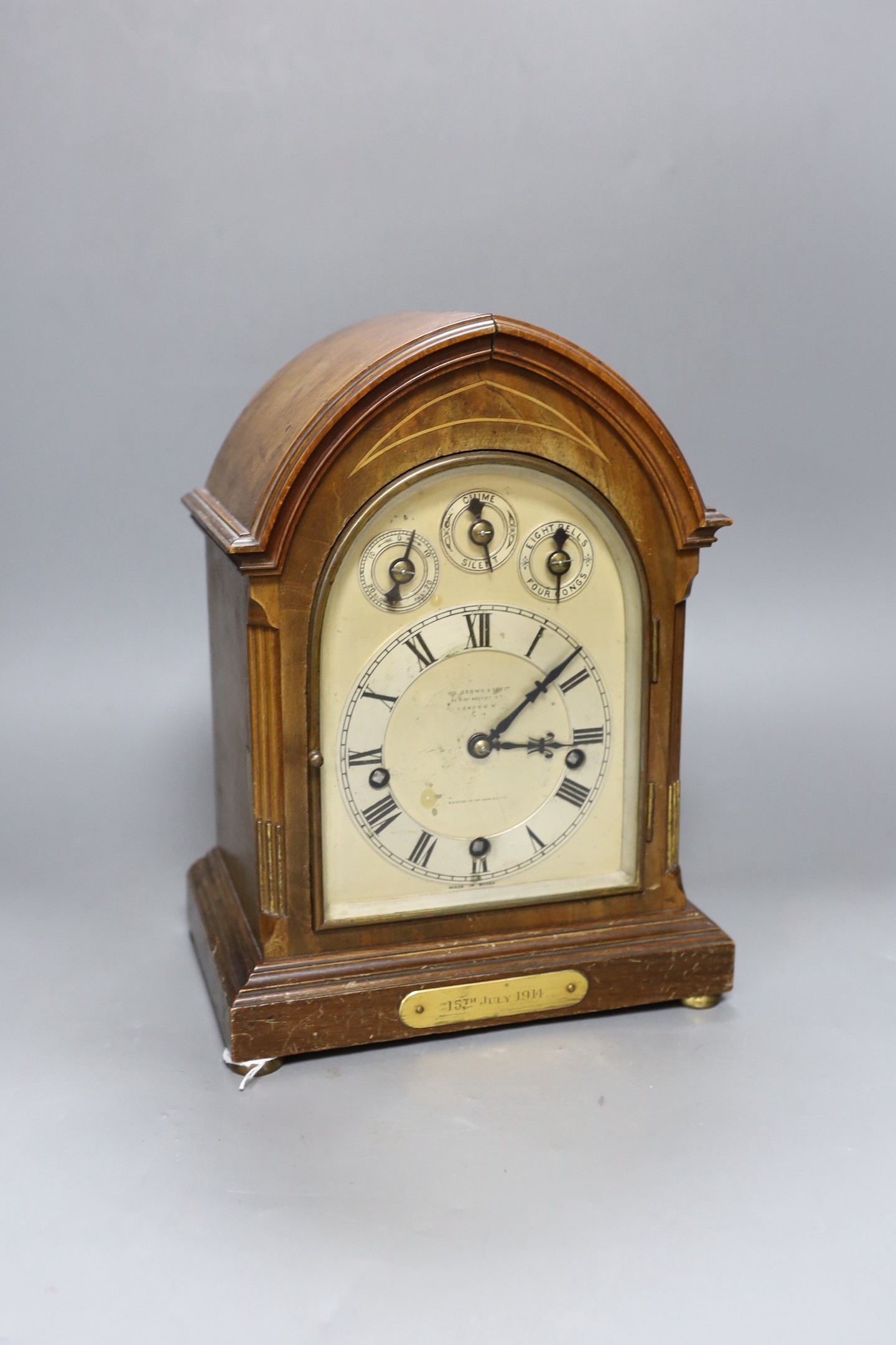 A George V inlaid walnut lancet shaped chiming mantel clock, with German movement and 15th July 1914 presentation plaque. 29cm high